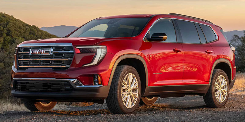 Red GMC Acadia SUV parked on a dirt path.
