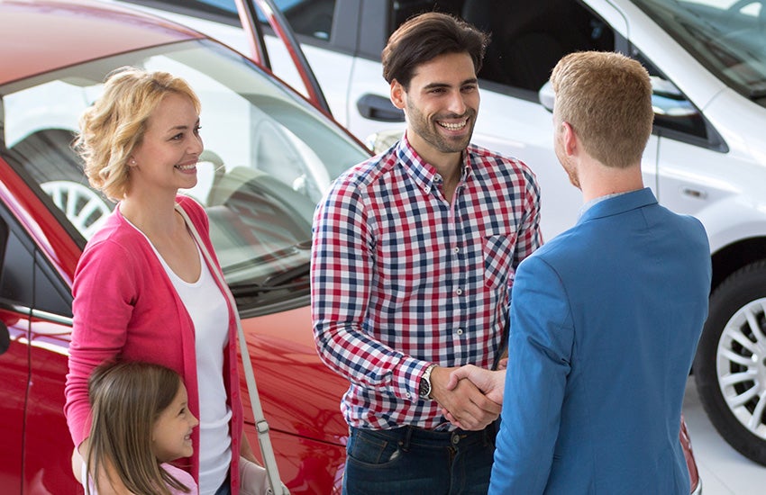 Two adults shaking hands with adult and child next to them